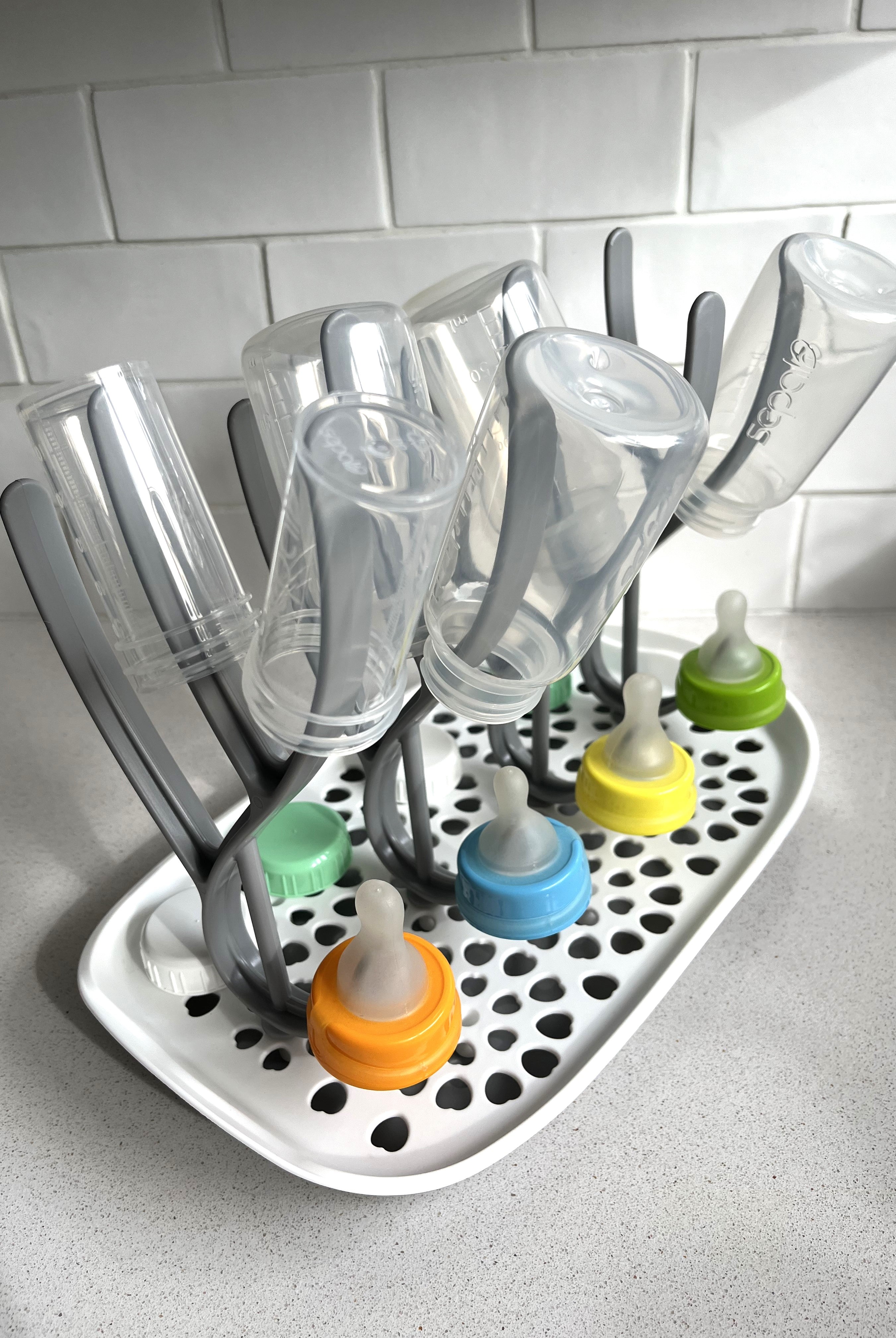 Baby bottle drying rack with an assortment of Sepal  bottles, teats and caps on the rack. Sitting on a kitchen bench.