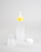 Sepal 250ml baby bottle with yellow medium teat medium flow attached. Beside the bottle is a white Sepal bottle cap and clear Sepal teat cover.