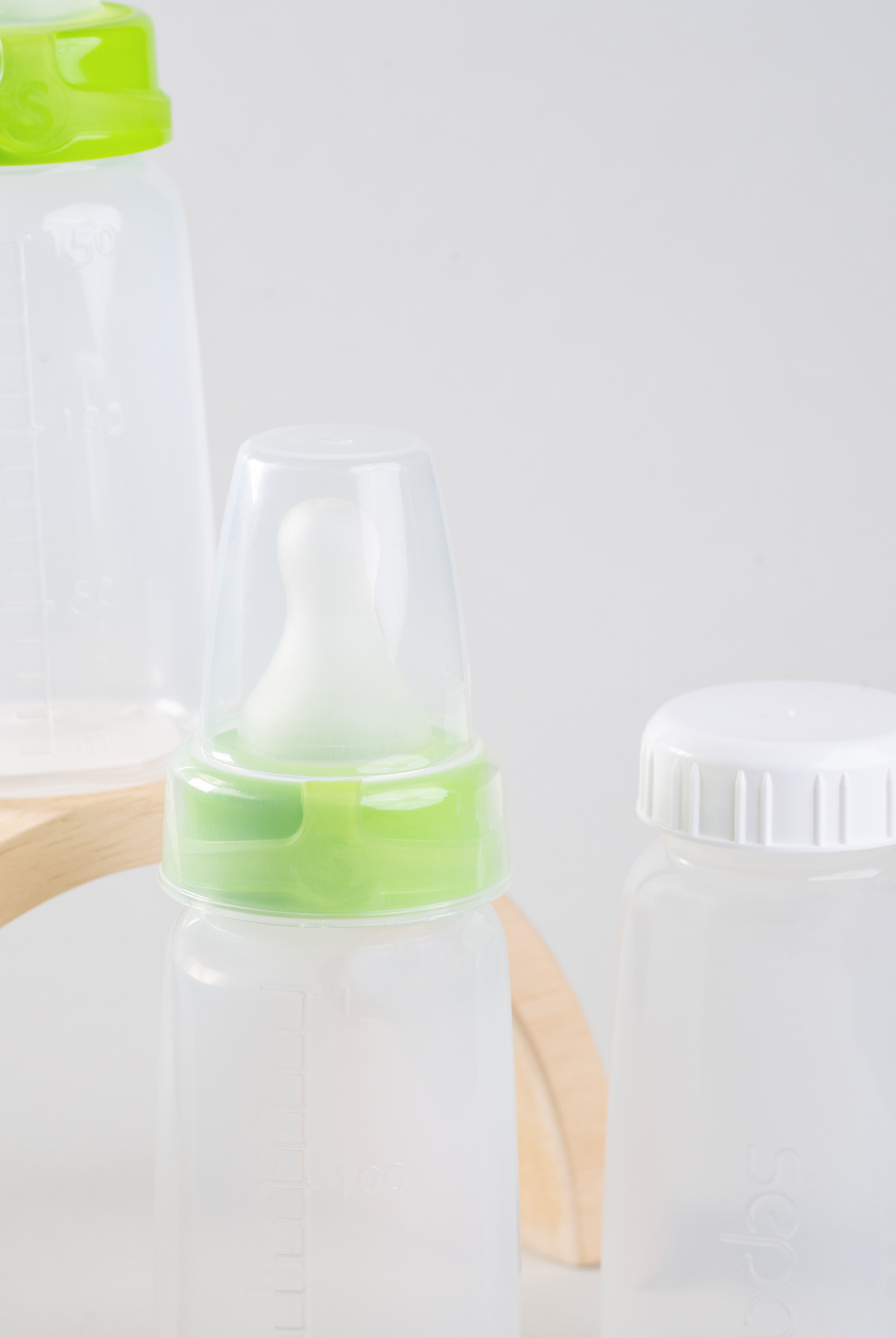 Close up photo of 2 sepal green small teat slow flow, 1 sepal white cap, 1 sepal clear teat cover and 3 sepal 150ml bottles