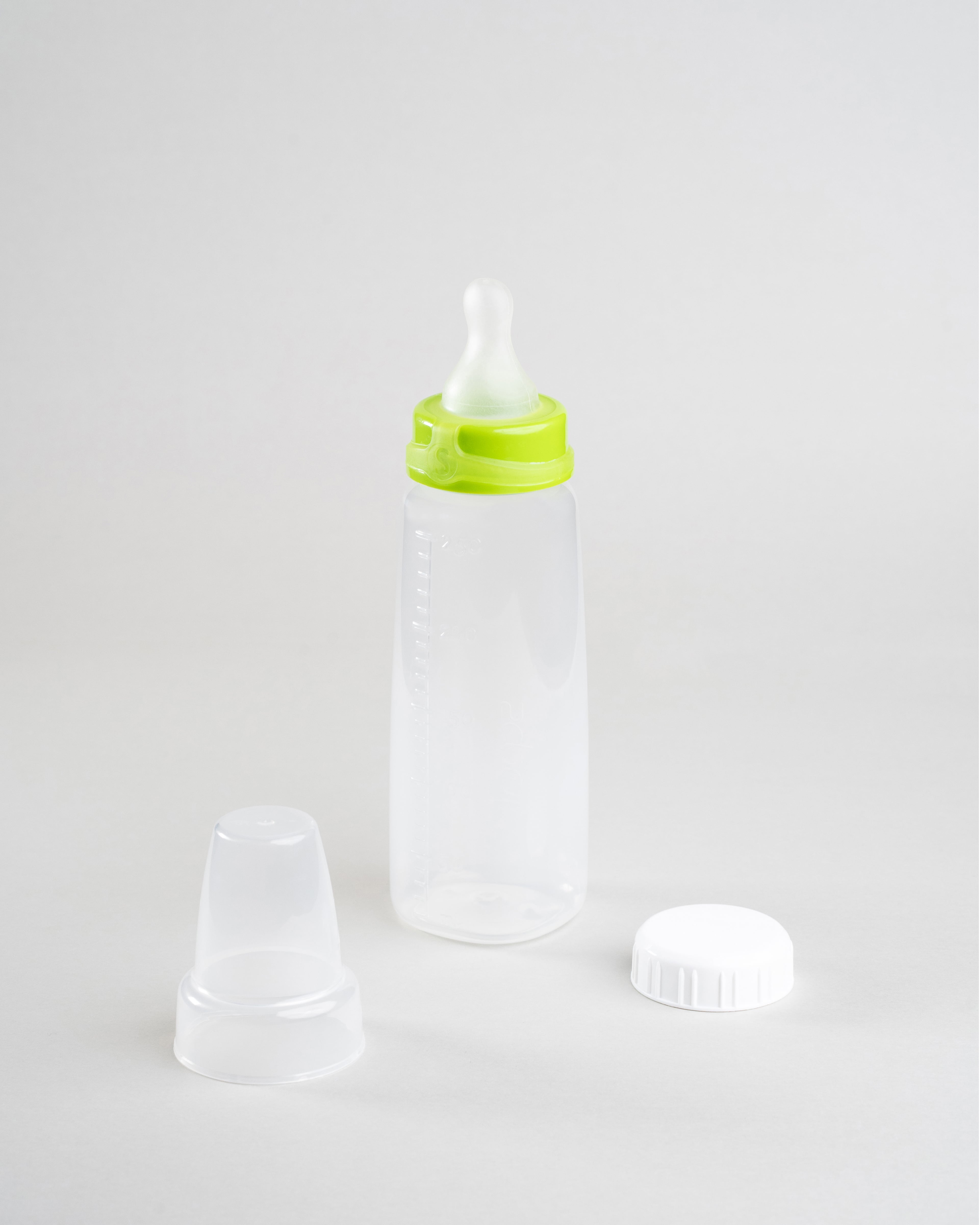 Sepal 250ml bottle with green small teat slow flow attached. Beside this is a Sepal white cap and a clear Sepal Teat Cover.
